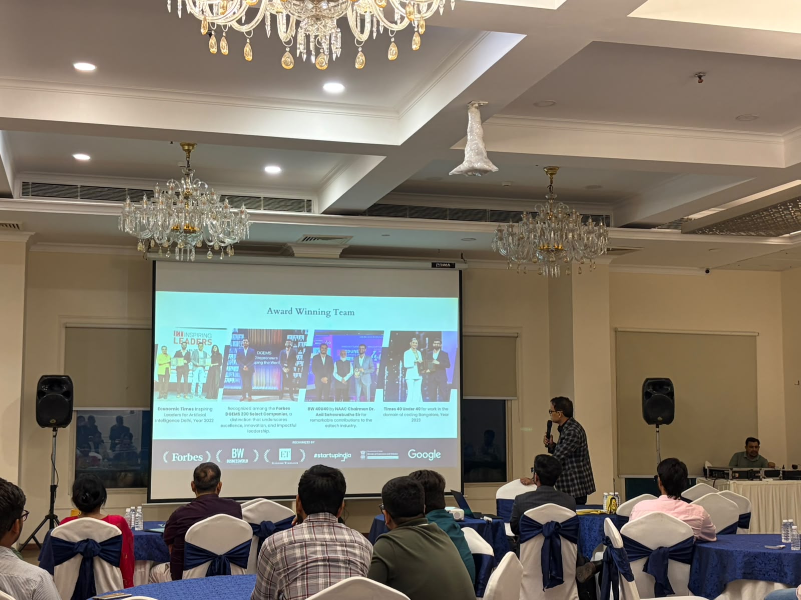 Mayank Saxena presenting Coding Pro's award-winning team slide to a seated audience